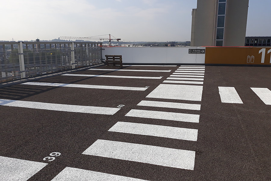 Abgesplittete Gussasphaltdeckschicht auf dem Dachgeschoss Parking Fort Neipperg mit markierten Stellplätzen.