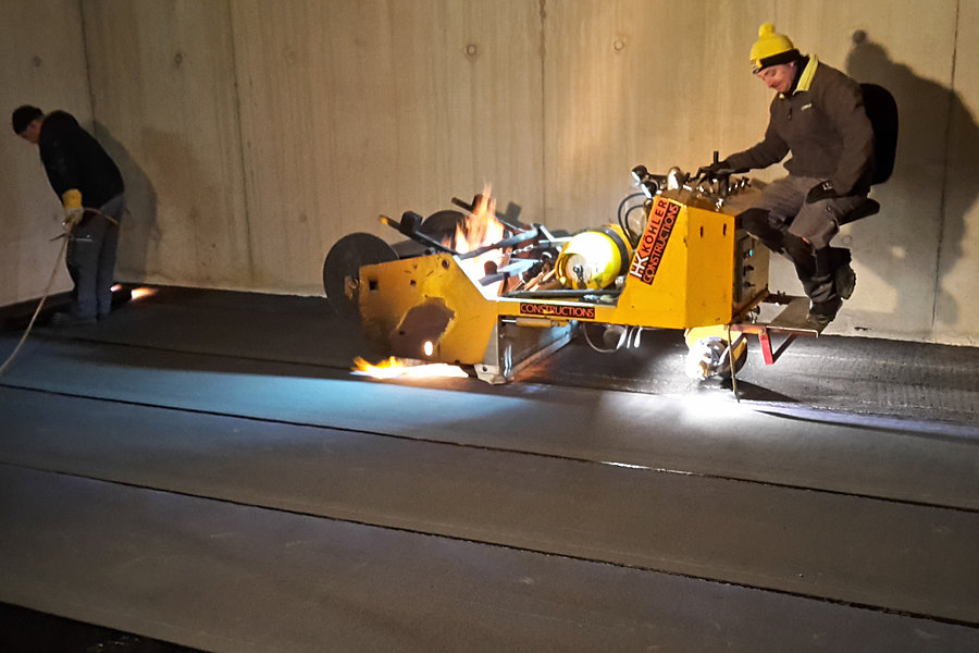 Maschinelle Verlegung von Bitumenschweißbahnen mit einer Schweißbahnverlegemaschine zur fachgerechten Bauwerksabdichtung, in Tiefgarage.