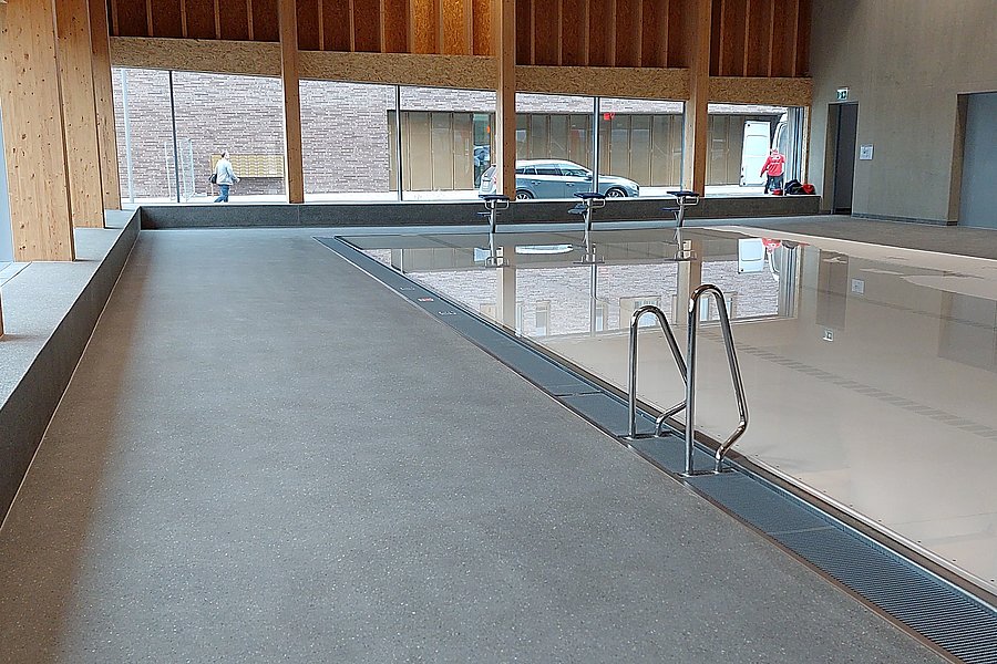 Geschliffener Gussasphalt BituTerrazzo als langlebiger Bodenbelag im Außenbereich eines öffentlichen Schwimmbads.