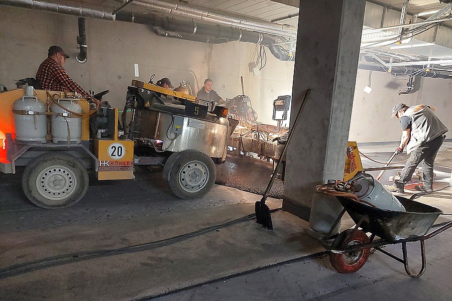 Fachgerechter Einbau einer langlebigen Gussasphaltschutzschicht mit einem Gussasphalt-Dumper in einer Tiefgarage.